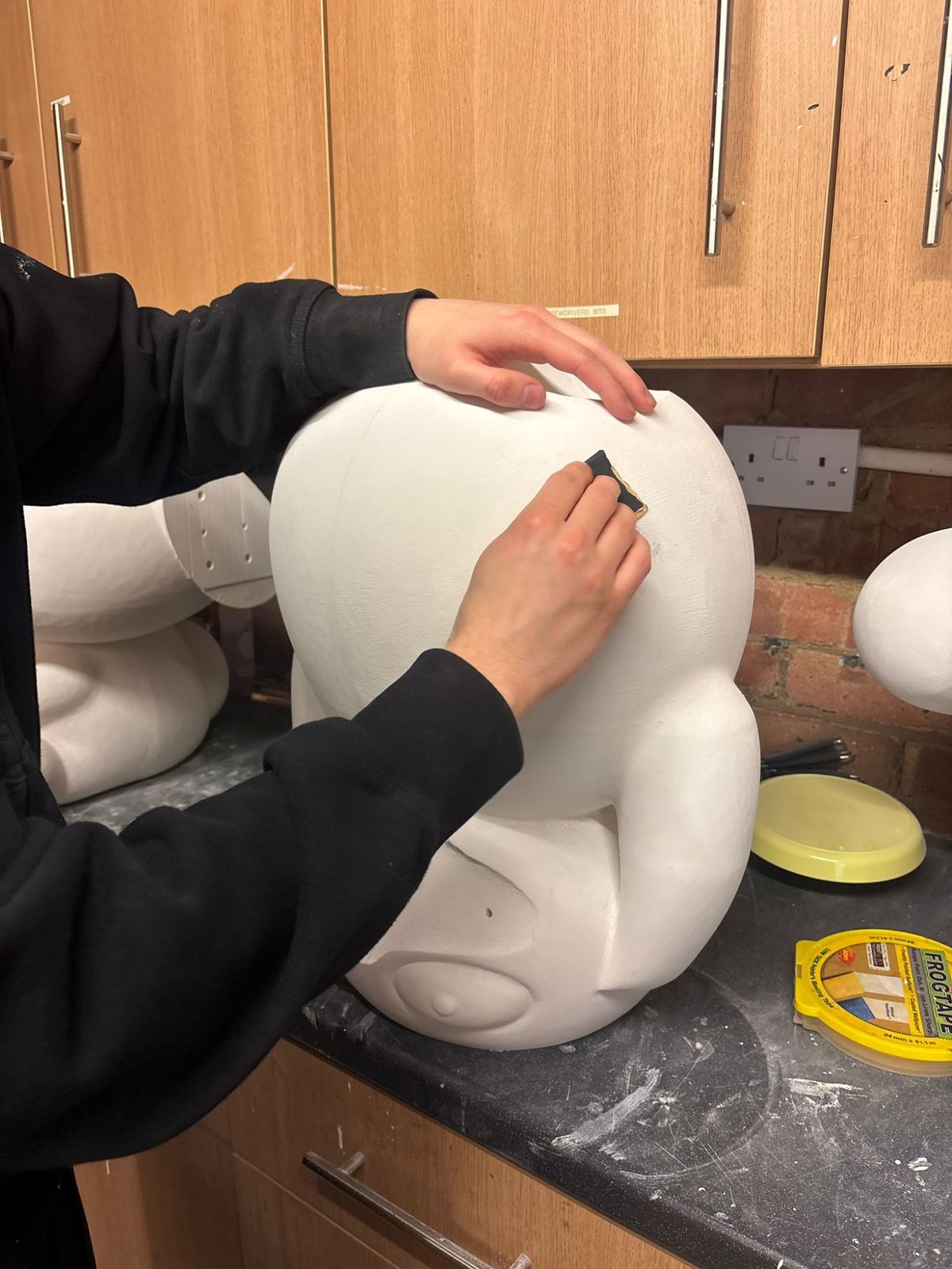 Hand-sanding a Psyduck sculpture with fine grit sandpaper